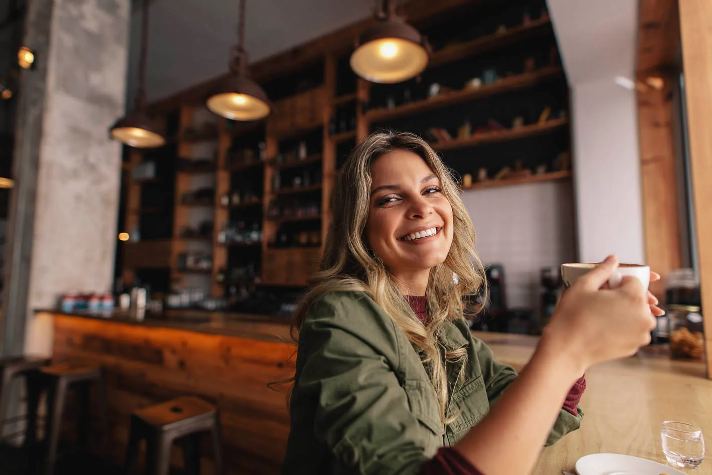 Eine junge Frau sitz in einem Café und trinkt einen Cappuccino