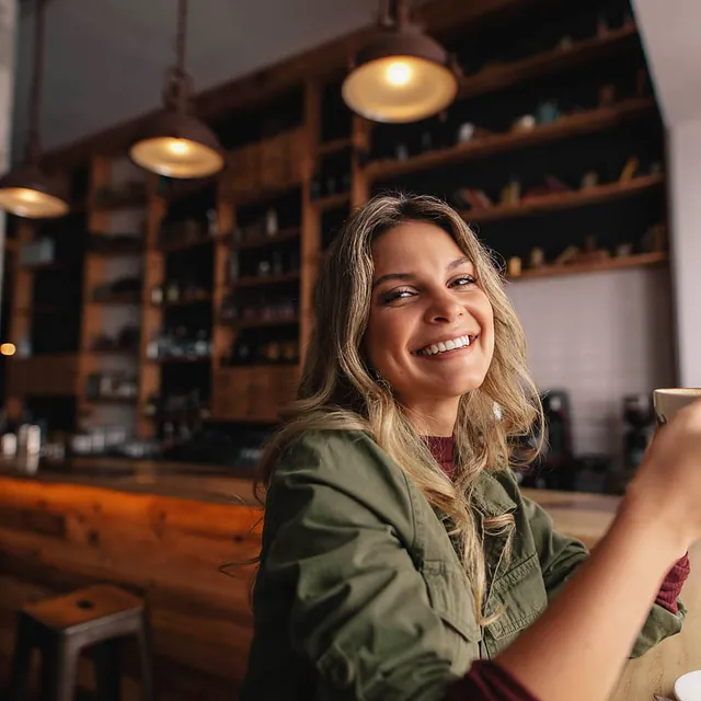 Eine junge Frau sitz in einem Café und trinkt einen Cappuccino